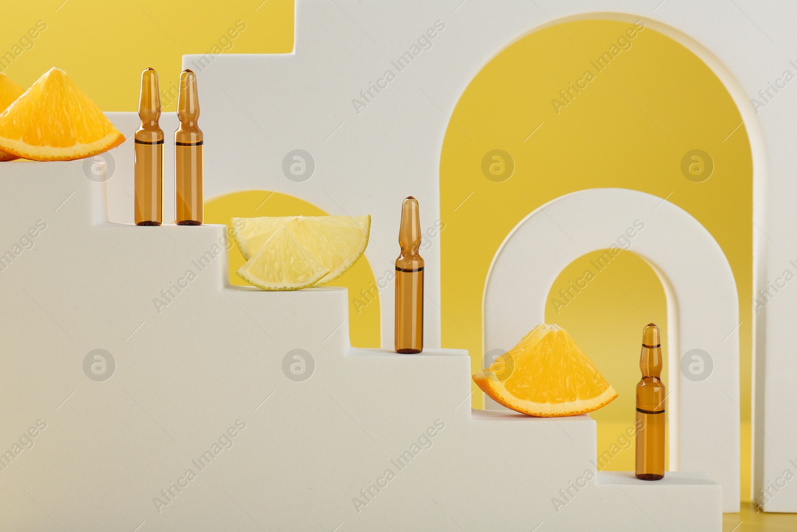 Photo of Stylish presentation of skincare ampoules with vitamin C and citrus slices on decorative stairs against yellow background, closeup