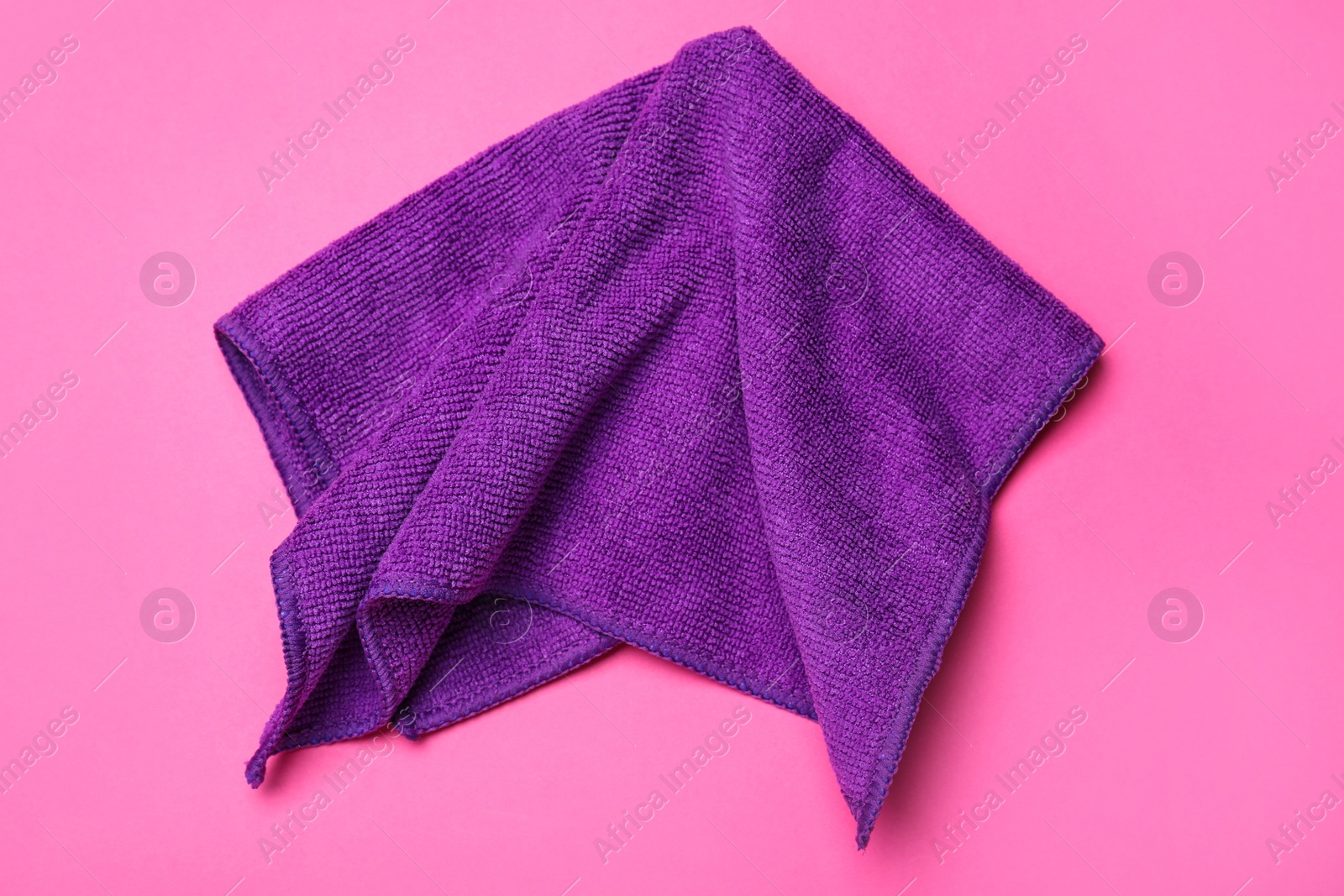 Photo of Purple microfiber  cloth on pink background, top view