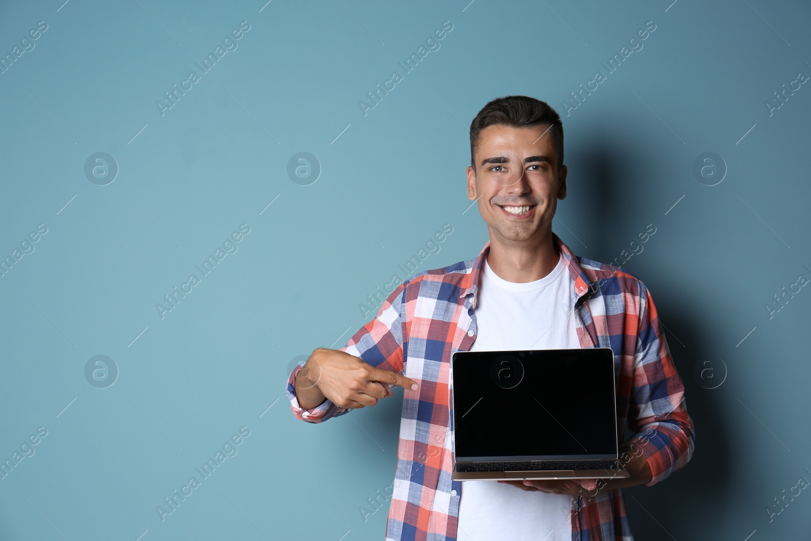 Photo of Man in casual clothes with laptop on color background