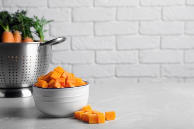 Photo of Bowl of fresh diced carrots on marble table. Space for text