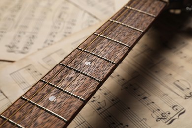 Photo of Guitar neck on paper sheets with music notes, closeup