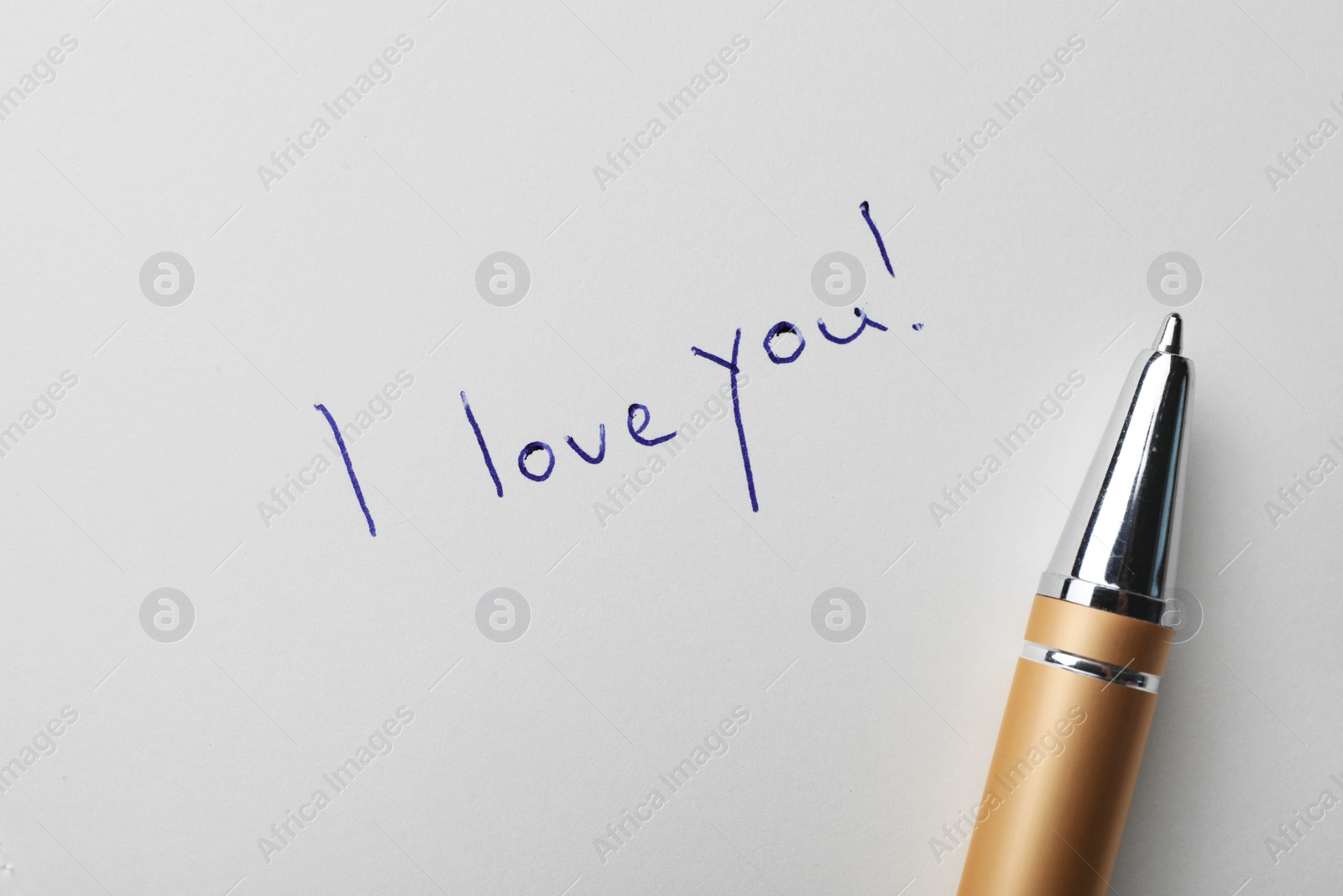 Photo of Written words I LOVE YOU and pen on white paper, top view