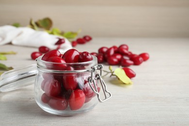 Photo of Fresh ripe dogwood berries in glass jar on white wooden table. Space for text