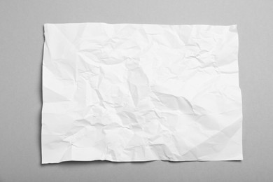 Photo of Sheet of white crumpled paper on grey background, top view