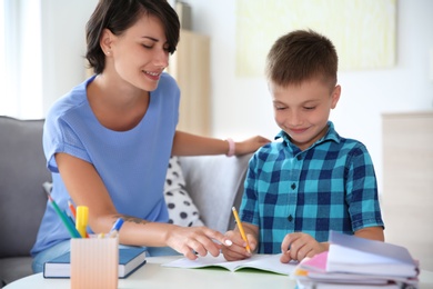 Photo of Young woman helping her child with homework at home. Elementary school