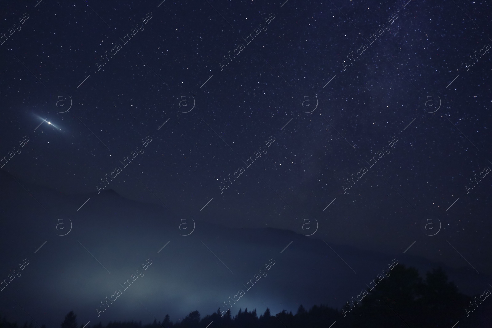 Photo of Picturesque view of night sky with beautiful stars over foggy hill