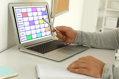 Photo of Young man using calendar app on laptop in office, closeup