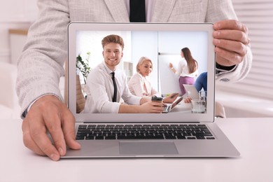 Businessman attending online video conference via modern laptop at table in office, closeup