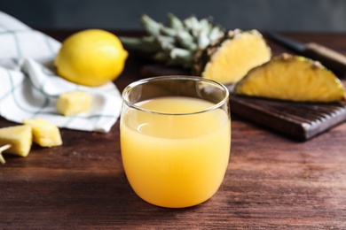 Photo of Fresh pineapple juice in glass on wooden table