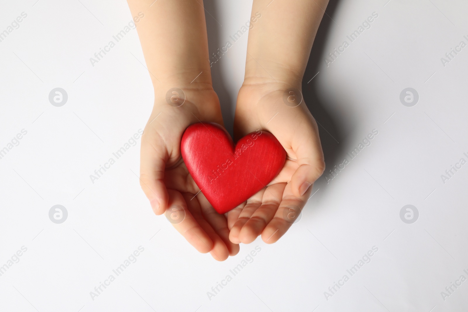 Photo of Woman holding red heart in hands on white background, top view