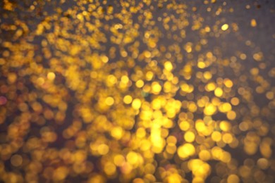 Photo of Blurred view of golden glitter on grey background. Bokeh effect