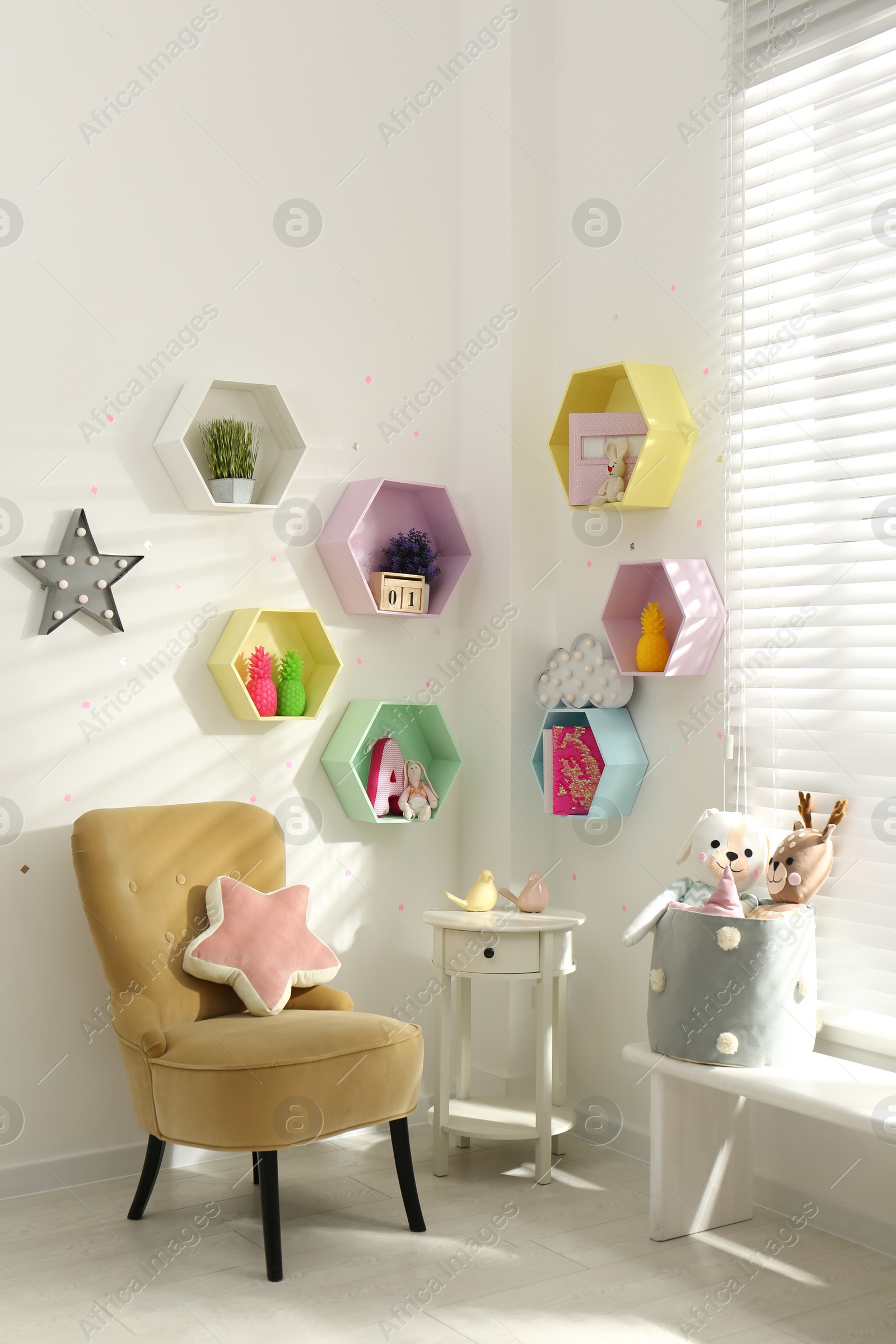 Photo of Hexagon shaped shelves on white wall in nursery. Interior design