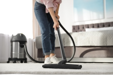 Photo of Woman removing dirt from carpet with vacuum cleaner at home, closeup