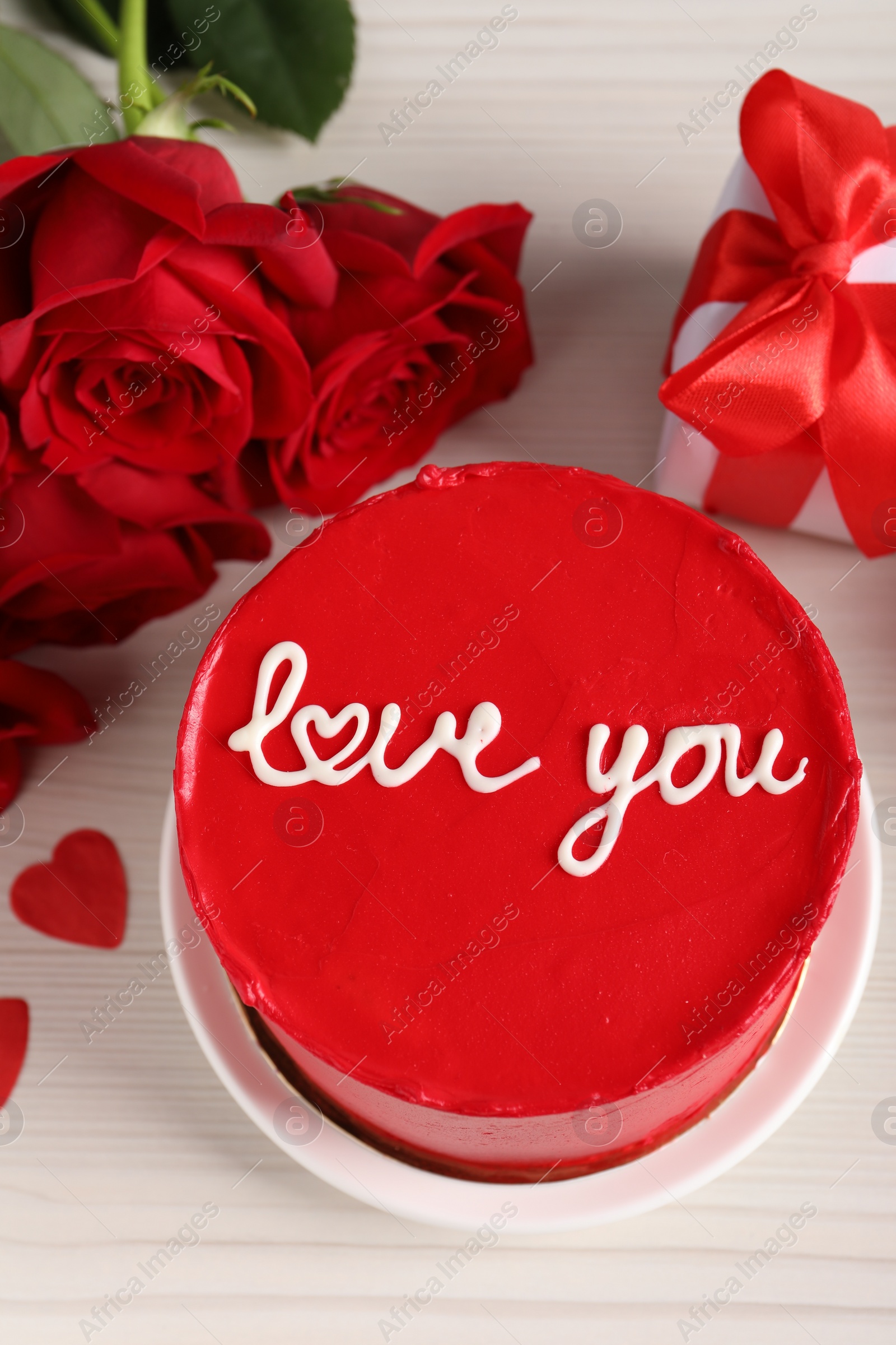 Photo of Bento cake with text Love You, roses and gift box on white wooden table, above view. St. Valentine's day surprise