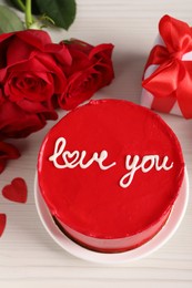 Bento cake with text Love You, roses and gift box on white wooden table, above view. St. Valentine's day surprise