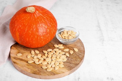 Photo of Fresh pumpkin and vegetable seeds on white table. Space for text