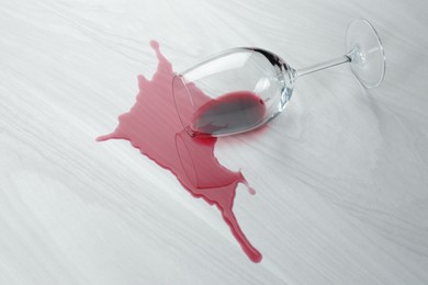 Overturned glass and spilled wine on white wooden table