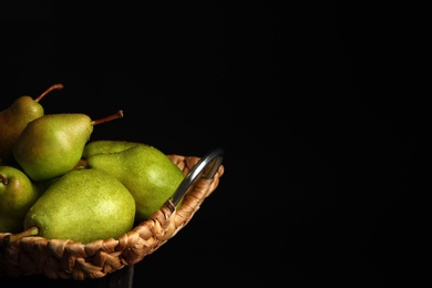 Photo of Tray with ripe pears on table against dark background. Space for text