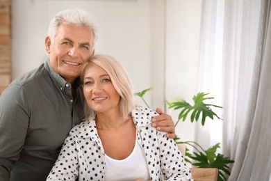 Portrait of affectionate senior couple at home. Space for text