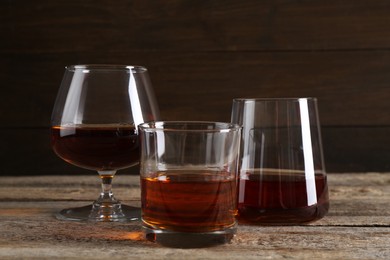 Different delicious liqueurs in glasses on wooden table