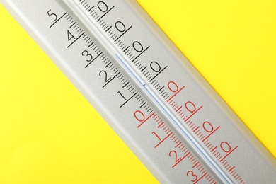 Modern weather thermometer on yellow background, closeup