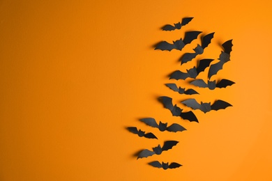 Photo of Paper bats on color background with space for text. Halloween decor