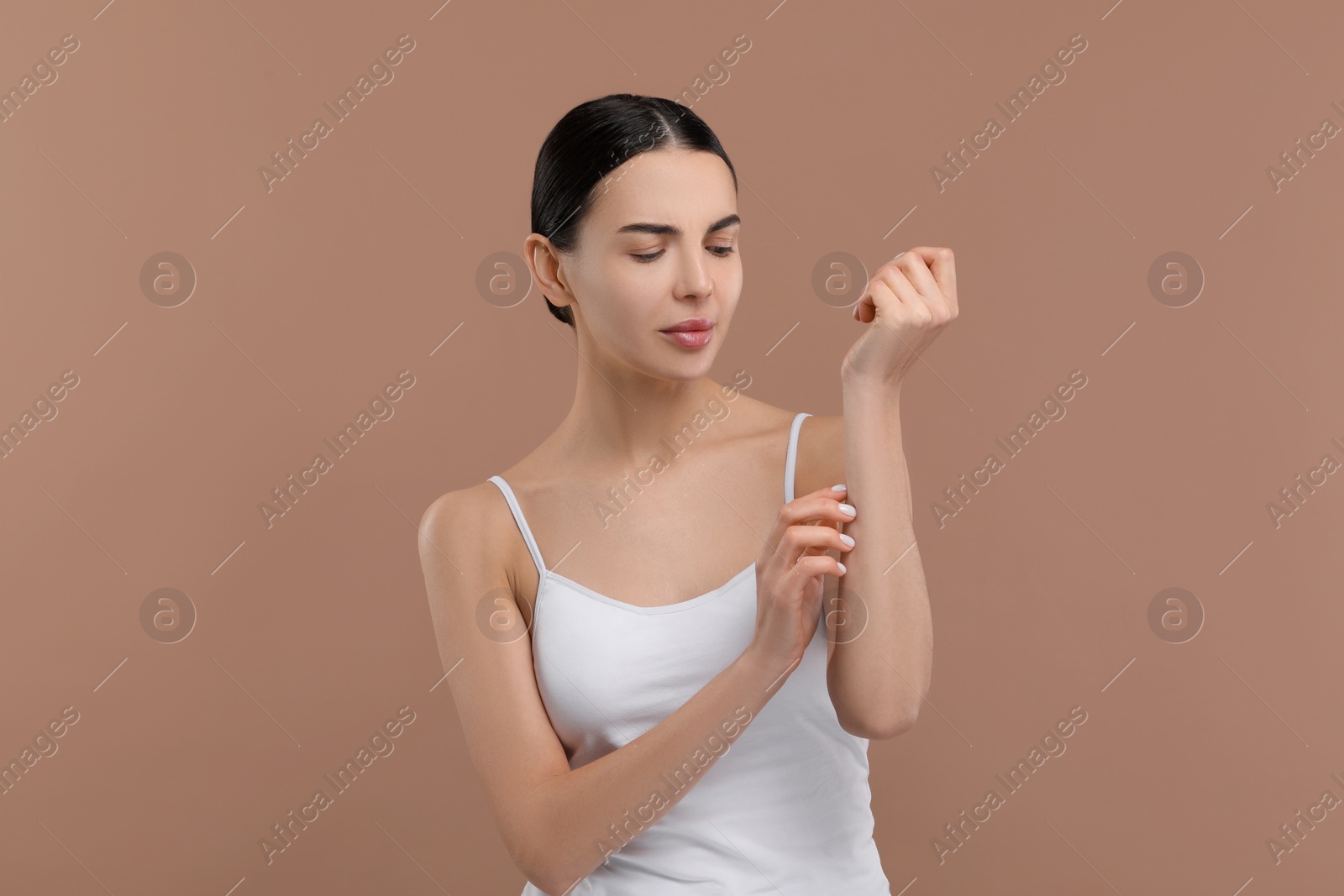 Photo of Woman with dry skin checking her arm on beige background