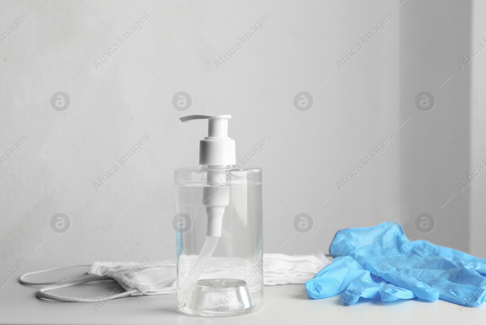 Photo of Antiseptic gel, protective gloves and masks on table indoors. Protection from virus