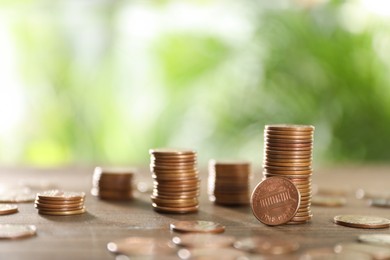 Many metal coins on wooden table against blurred green background