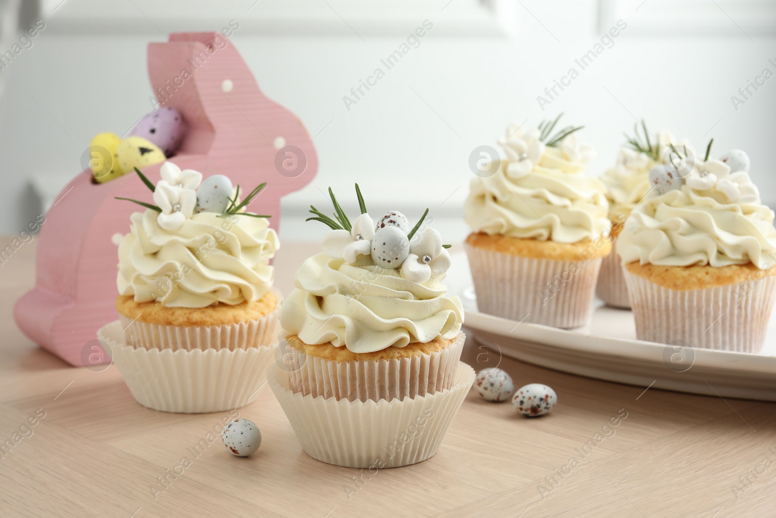 Photo of Tasty Easter cupcakes with vanilla cream on wooden table