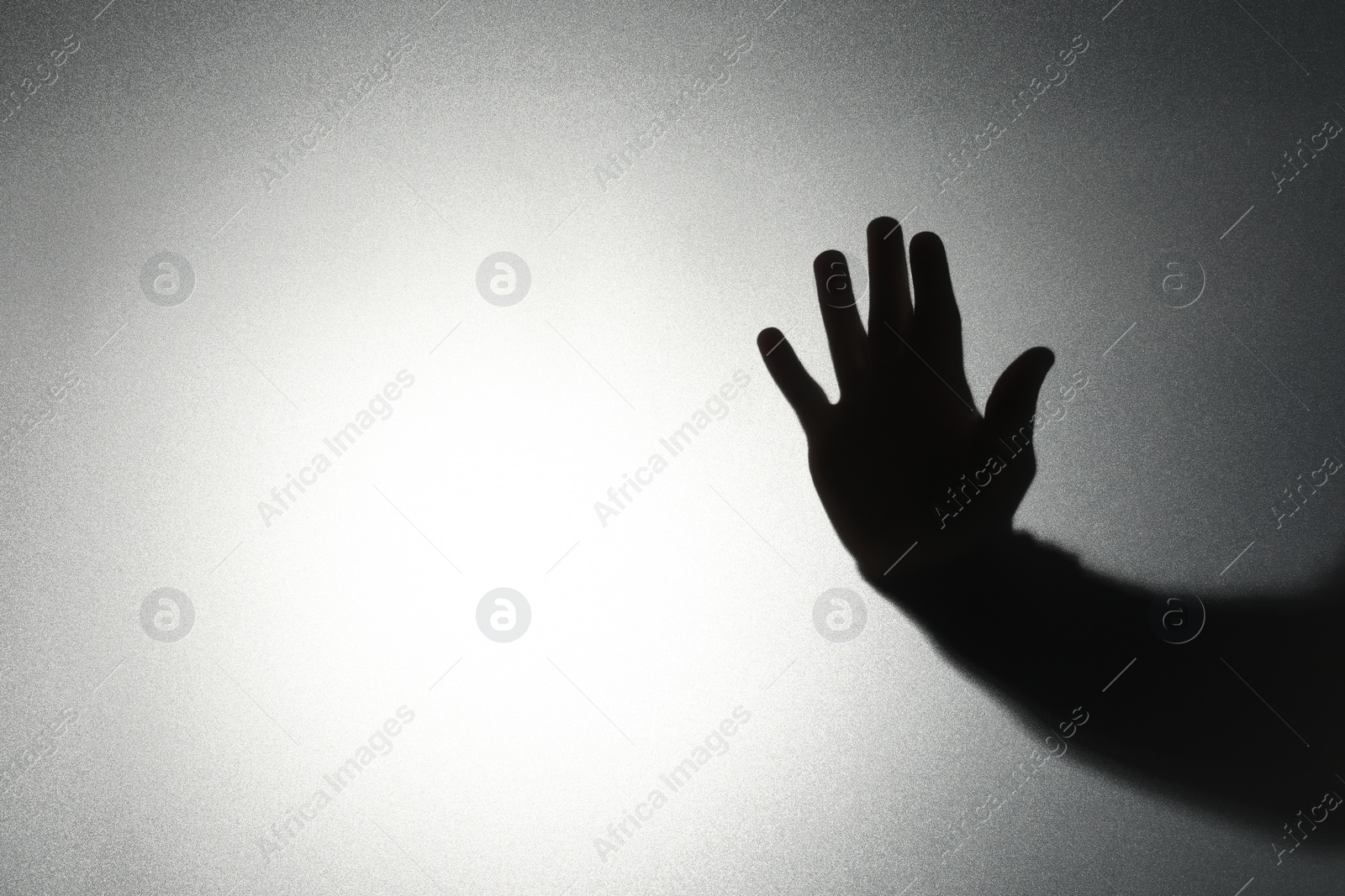 Photo of Silhouette of ghost behind glass against light background, closeup. Space for text