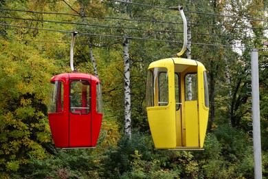 View of cableway with bright cabins in park on autumn day