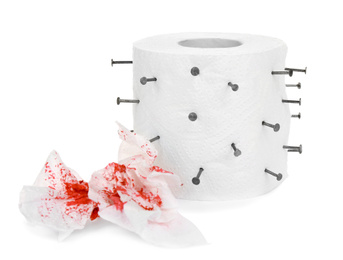 Roll of toilet paper with nails on white background. Hemorrhoid problems