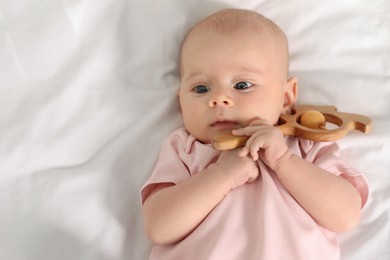 Photo of Cute little baby with toy on white sheets, top view. Space for text