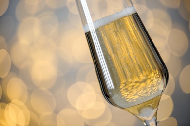 Photo of Glass of champagne on blurred background, closeup. Space for text