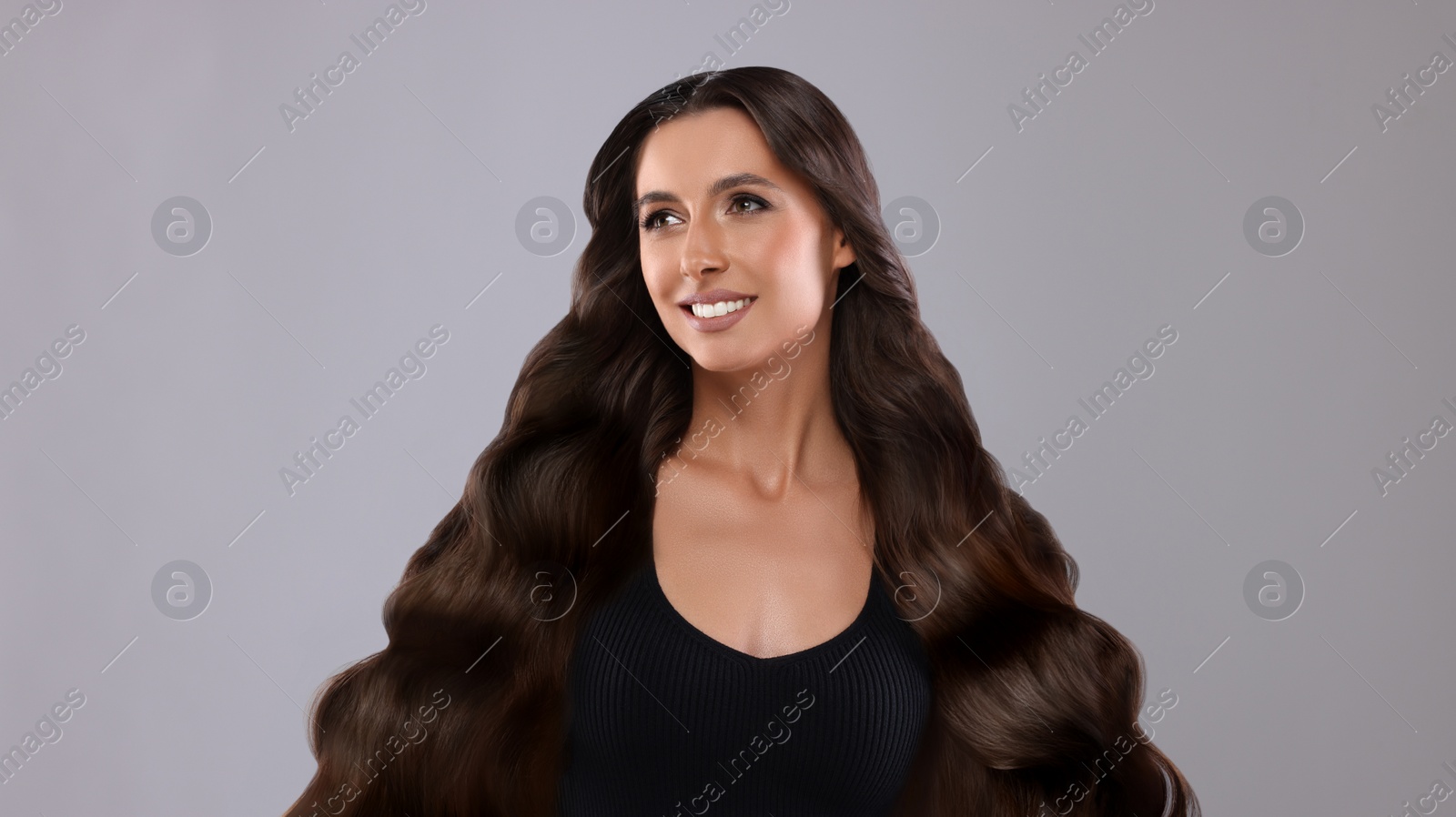 Image of Hair styling. Attractive woman with wavy long hair on grey background, banner design