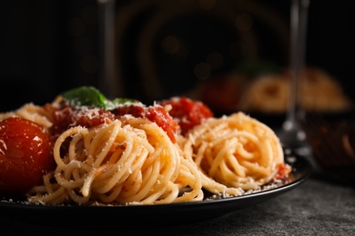 Photo of Tasty pasta with basil, tomatoes and cheese on grey table. Closeup