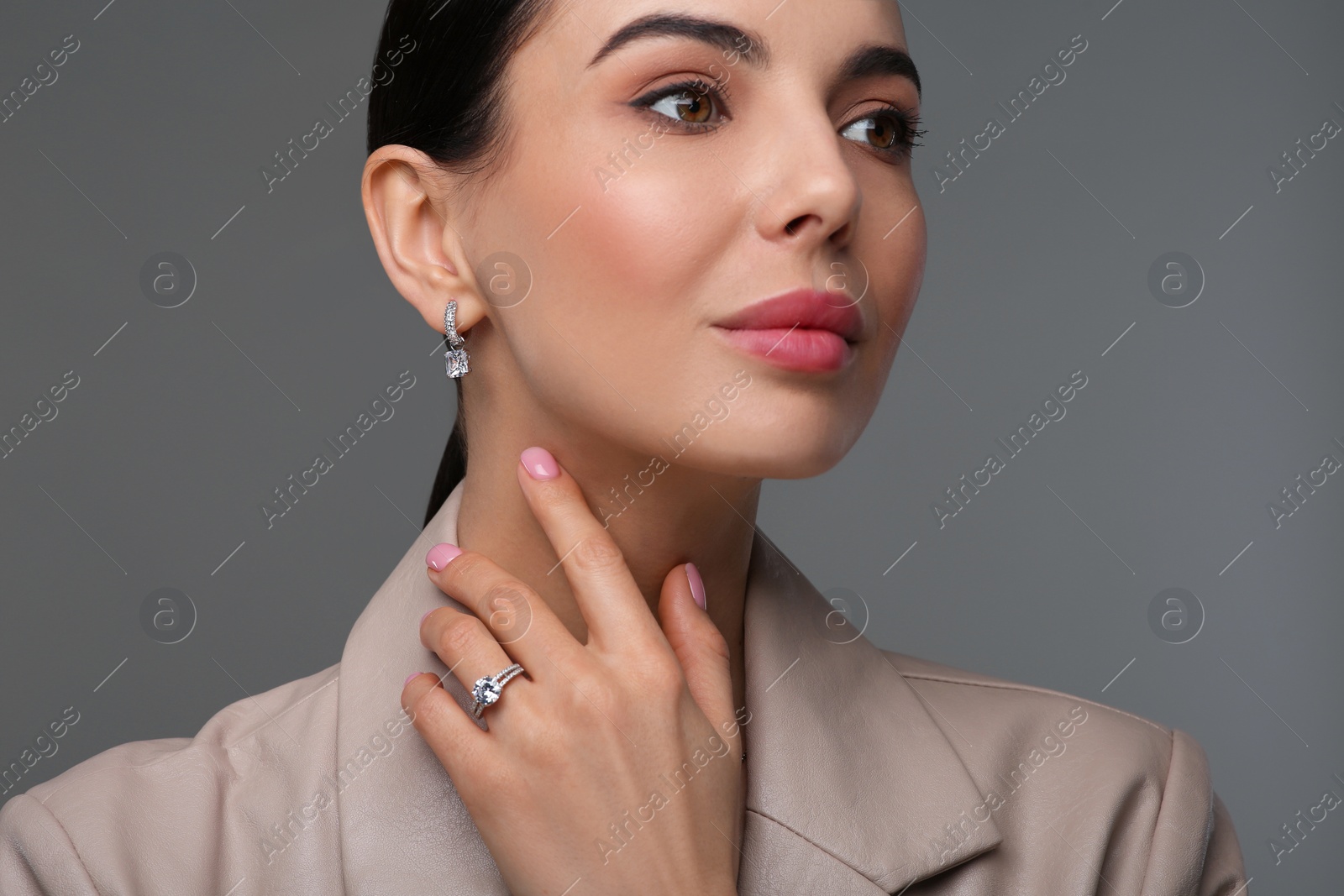 Photo of Young woman with elegant jewelry on dark grey background, closeup