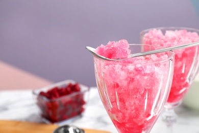 Spoon of raspberry snow ice cream on glass against blurred background. Space for text