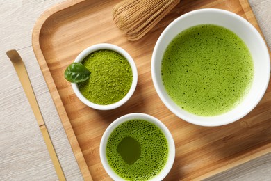 Fresh matcha tea, bamboo whisk, spoon and green powder on wooden table, top view