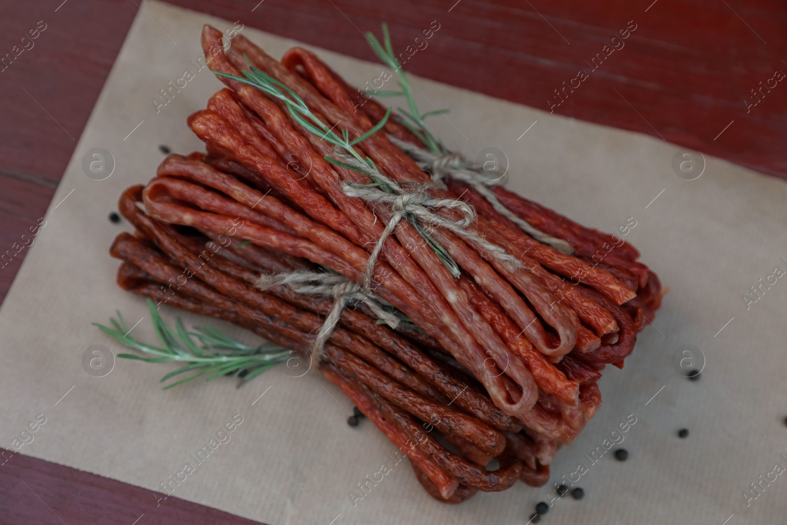 Photo of Tasty dry cured sausages (kabanosy) and spices on wooden table, above view