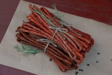 Photo of Tasty dry cured sausages (kabanosy) and spices on wooden table, above view