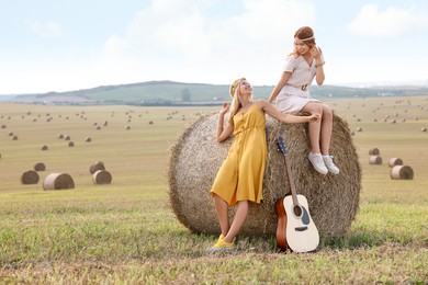 Photo of Beautiful hippie women with guitar in field, space for text