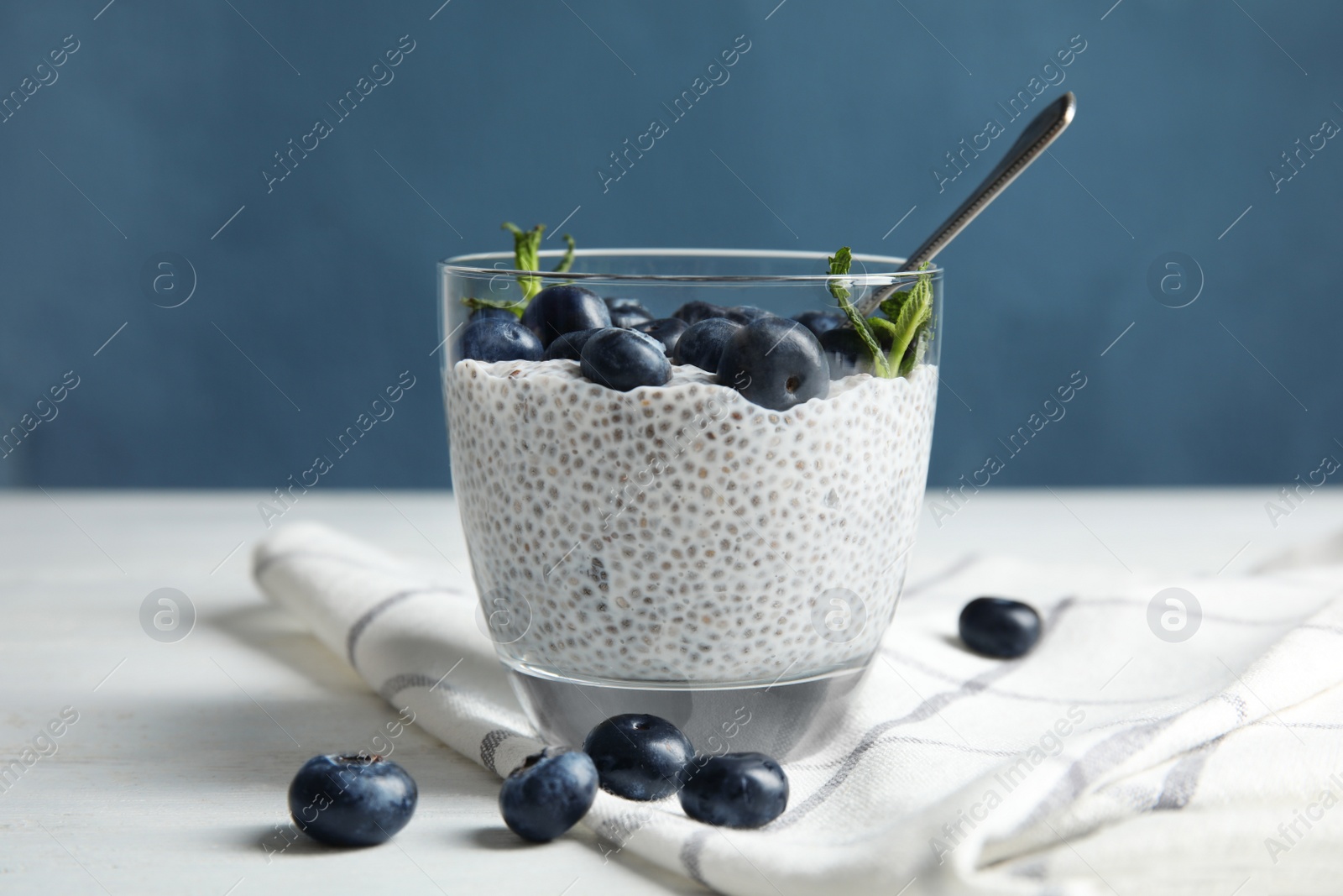 Photo of Tasty chia seed pudding with blueberries in glass on table