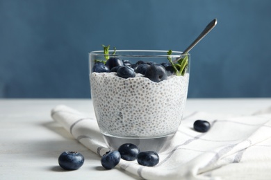 Tasty chia seed pudding with blueberries in glass on table