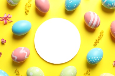 Photo of Flat lay composition with painted Easter eggs and blank card on color background, space for text