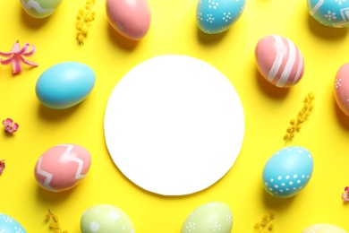 Flat lay composition with painted Easter eggs and blank card on color background, space for text