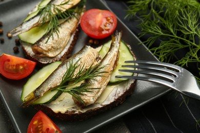 Photo of Delicious sandwiches with sprats, cucumber and dill served on plate, closeup