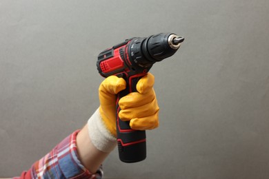 Photo of Handyman holding electric screwdriver on grey background, closeup