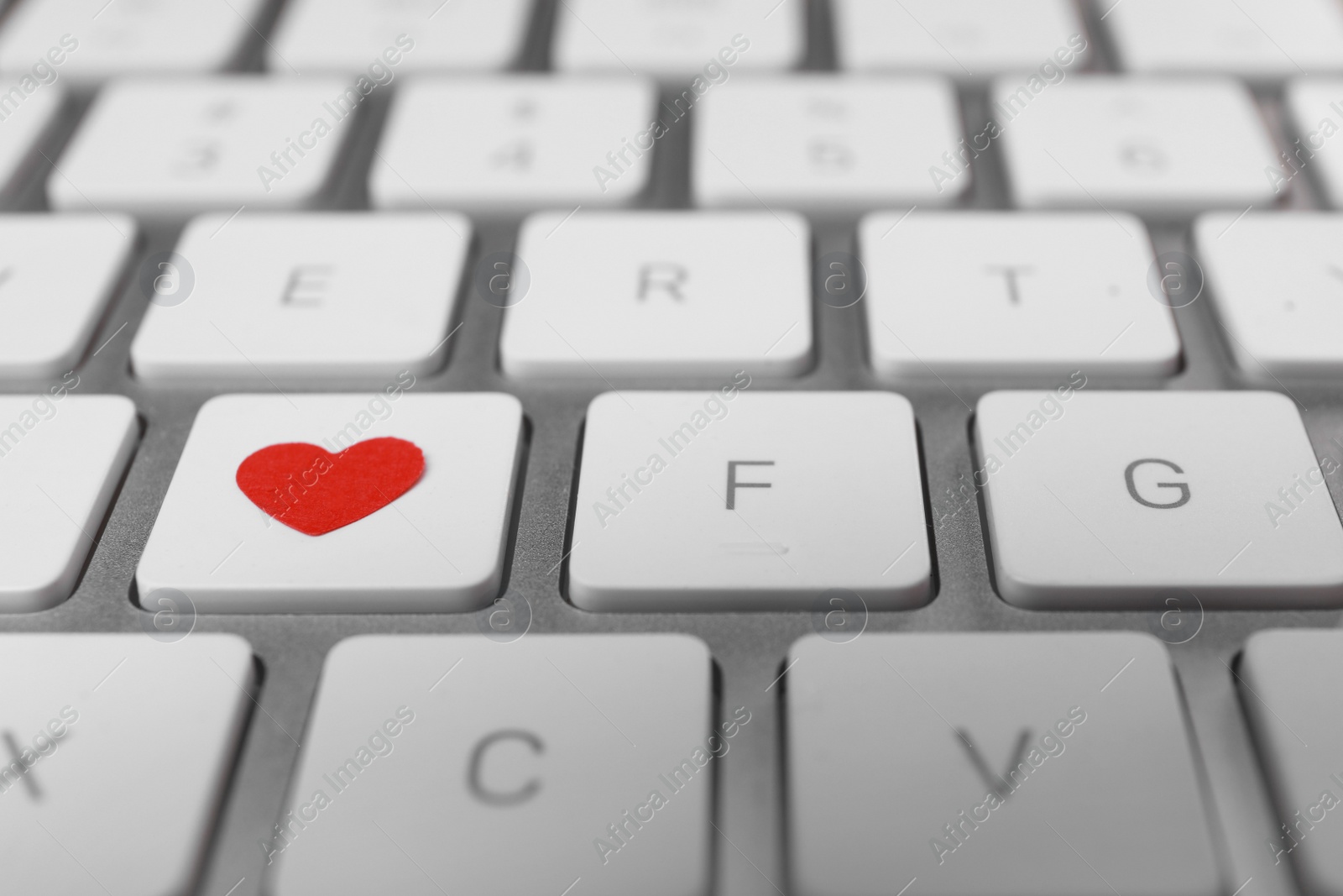 Photo of Heart on laptop keyboard, closeup. Online dating concept